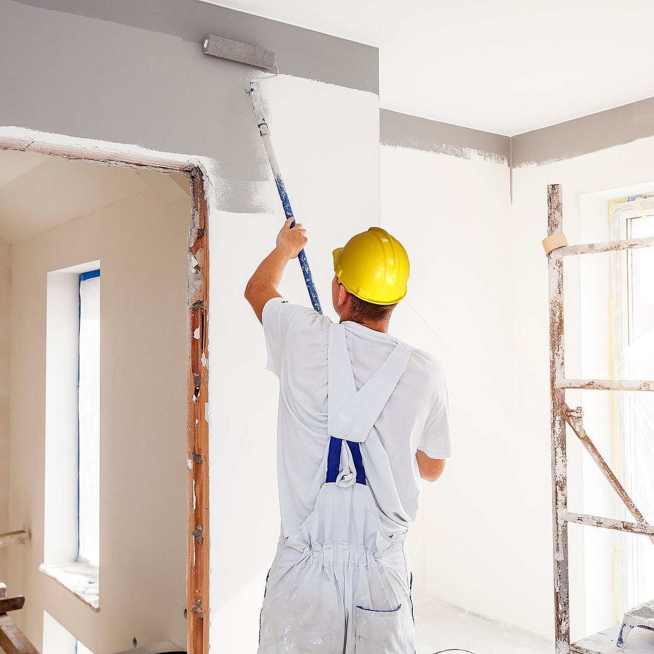 House painter paints a wall in a new home. Unrecognizable Person. Handwerker montiert Gipskartonwand - moderner Innenausbau mit System