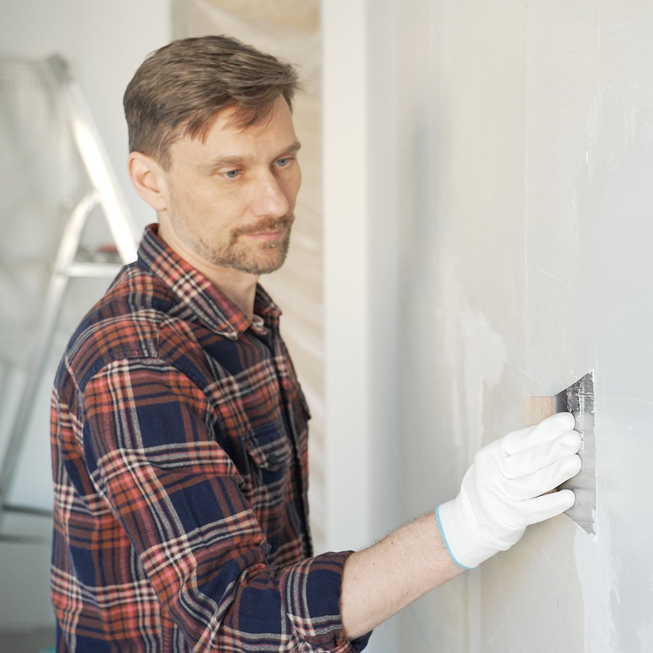 Handwerker verputzt Wand mit Kelle - präzise und sauber ausgeführt