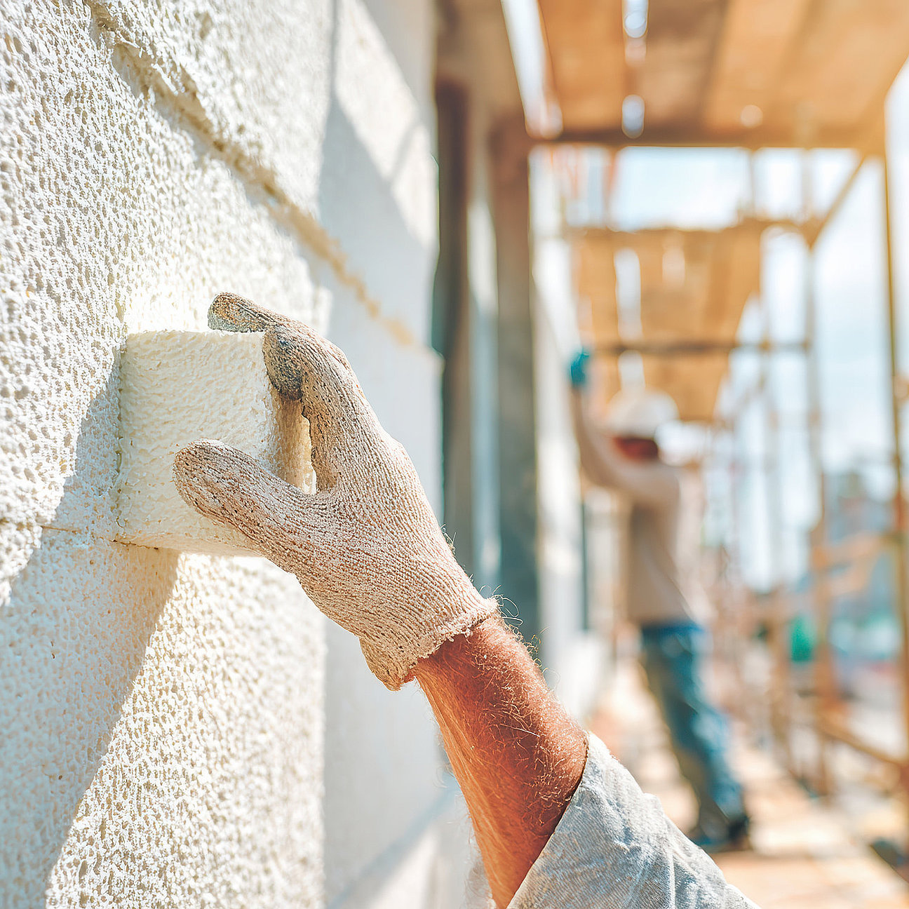 Focused worker on scaffolding during construction renovation installs foam insulation on an exterior wall of building for thermal efficiency Wandgestaltung mit Akzentfarben