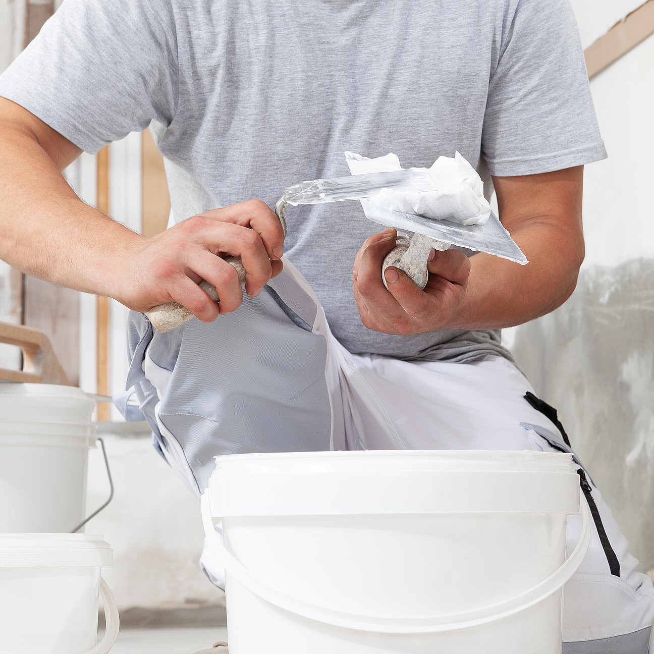 Hands man plasterer construction worker at work closeup, takes plaster from bucket and puts it on trowel to plaster the wall, inside the building site of a house Professionelle Verputzarbeiten an Fassade und Innenwand - Crössmann Baudekoration