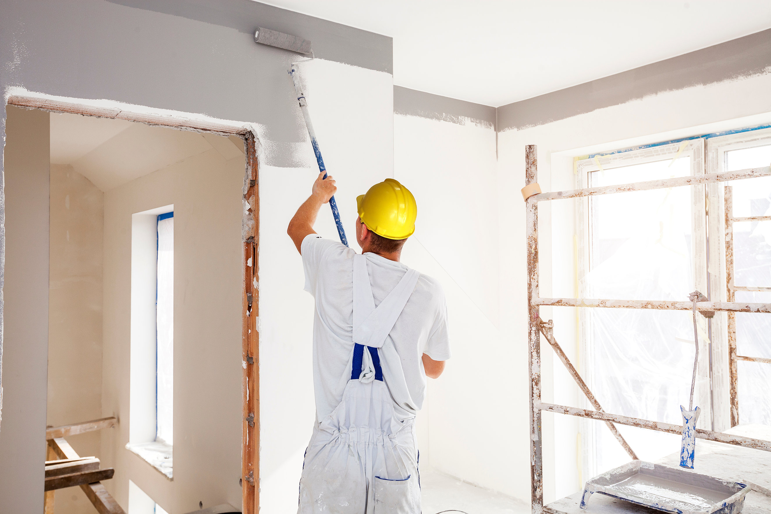 House painter paints a wall in a new home. Unrecognizable Person. Handwerker montiert Gipskartonwand - moderner Innenausbau mit System